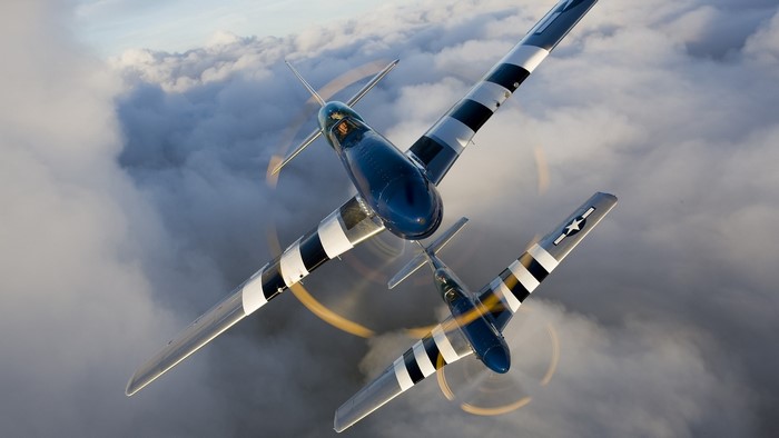Two P-51 Mustang aircraft flying through clouds
