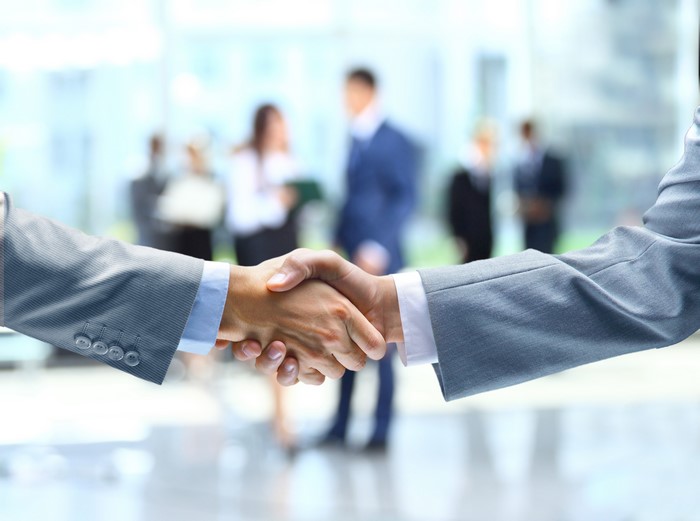 Two men in suits shaking hands in an office