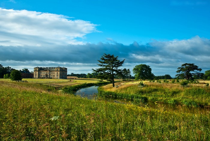 Country house with river and trees under blue sky