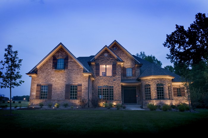 Brick and stone mansion at night with exterior lights