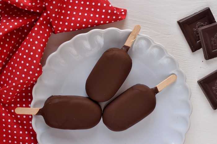 Chocolate-covered ice cream bars on a plate with chocolate squares