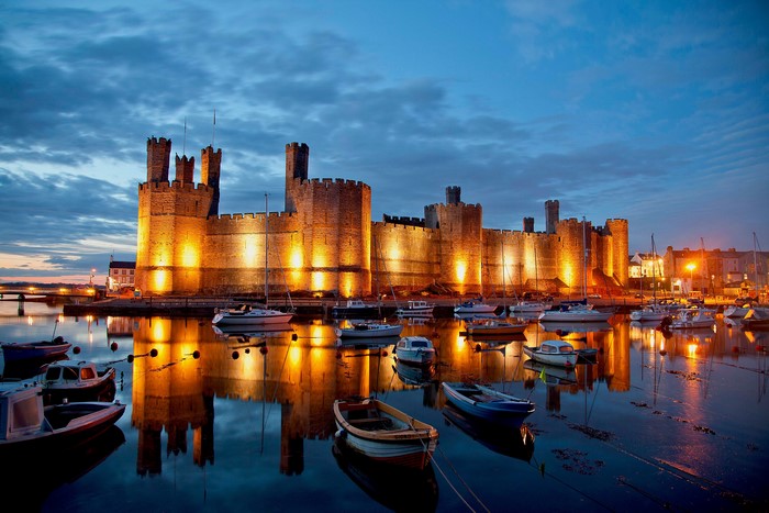 Caernarfon Castle and boats in Wales at dusk