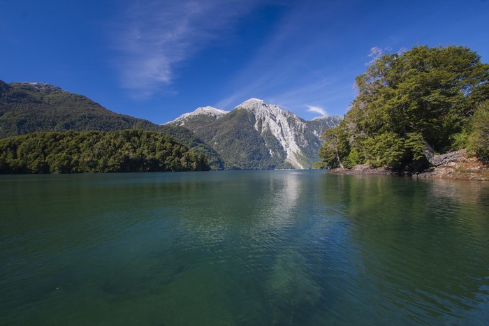 Lake and mountains with trees under a blue sky