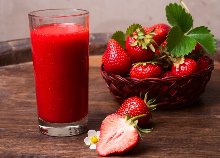 Strawberry juice in a glass with fresh strawberries