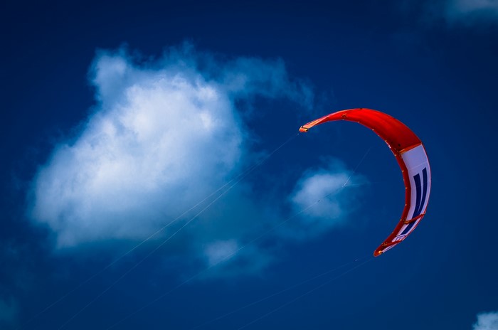Red kite flying in a blue sky with clouds