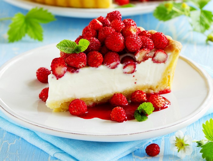Slice of strawberry tart with cream and wild strawberries