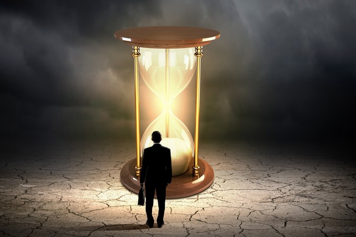 Man in suit looking at a glowing hourglass