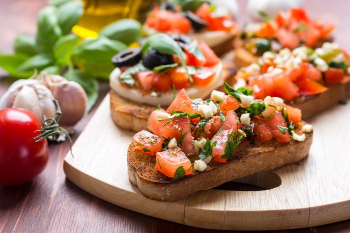 Bruschetta with tomatoes, basil, and olives on a wooden board