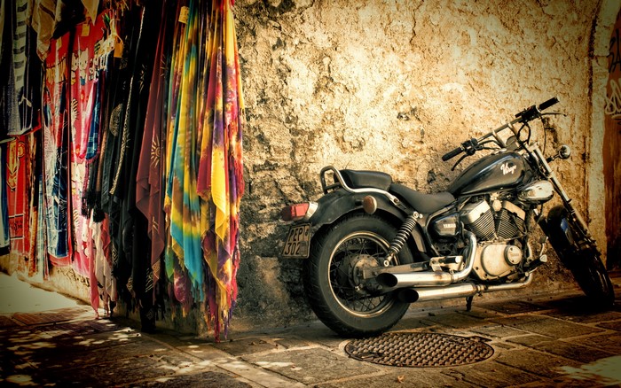 Motorcycle parked by colorful fabrics on a street