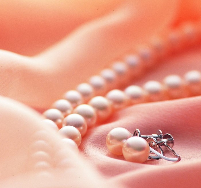 Pearl necklace and earrings on pink silk