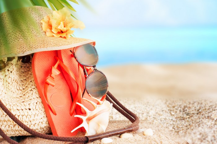 Summer beach accessories: hat, flip-flops, sunglasses, and seashell