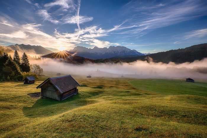Wooden cabins in a misty mountain valley at sunrise