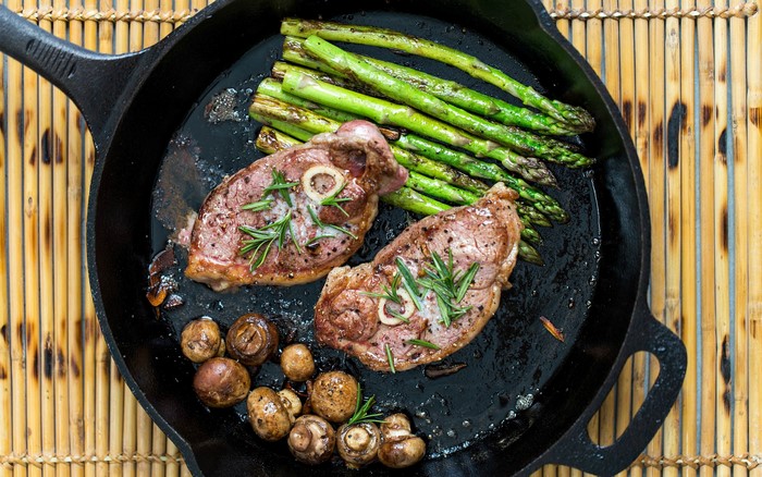 Lamb chops with asparagus and mushrooms in a cast iron skillet