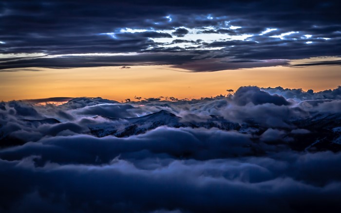 Dramatic sunset over mountains covered in clouds