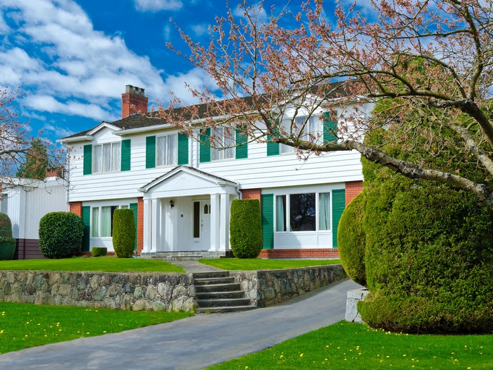 White house with green shutters and stone wall