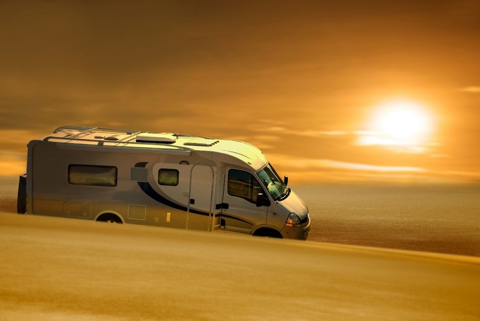 Motorhome driving through desert at sunset