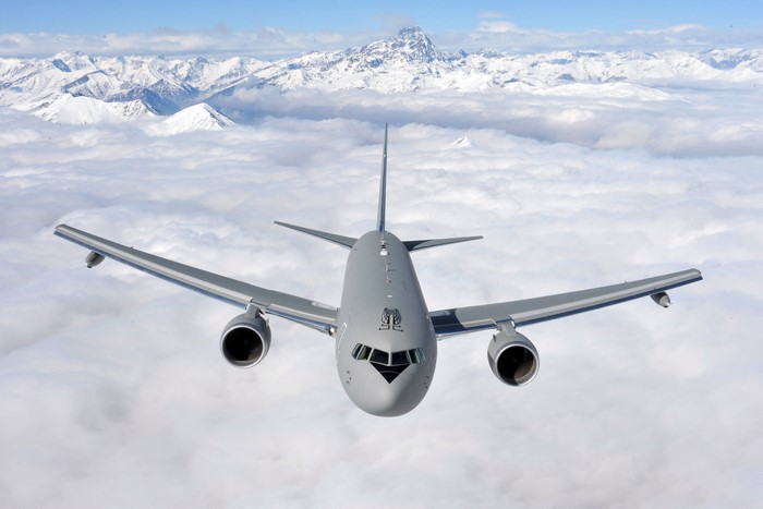 Boeing KC-767A airplane flying over clouds and mountains