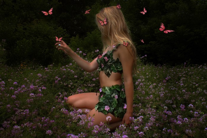 Blonde girl with butterflies in a field of flowers