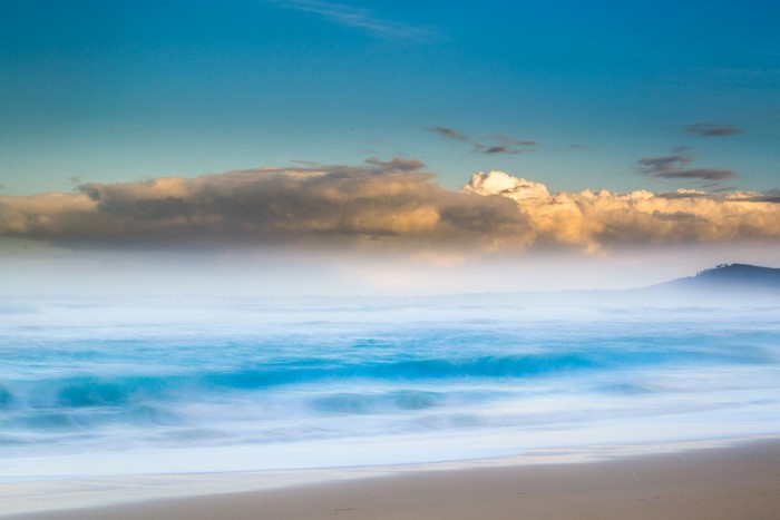 Ocean waves under clouds and blue sky