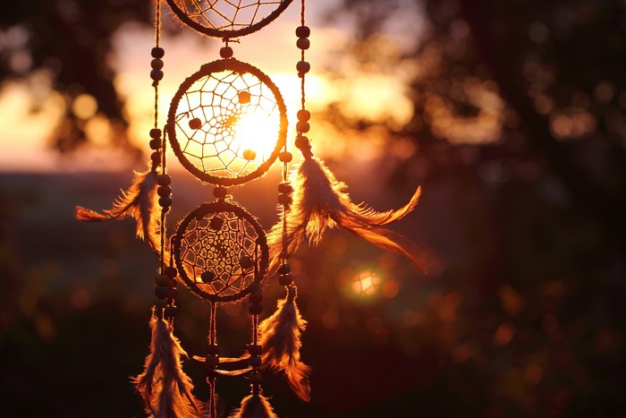 Dreamcatcher with feathers at sunset