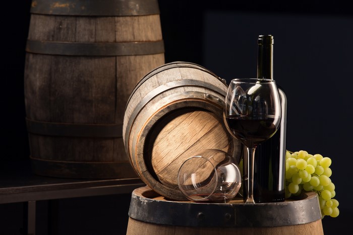 Wine bottle, glass, grapes, and barrels