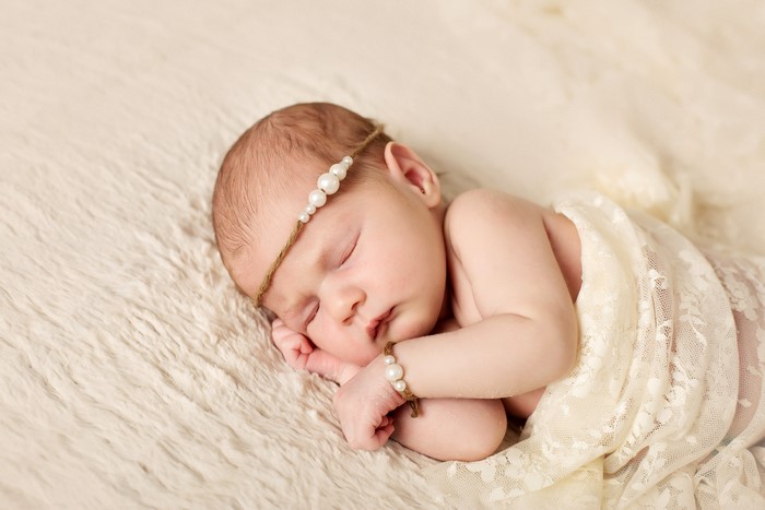Newborn baby sleeping with pearl jewelry