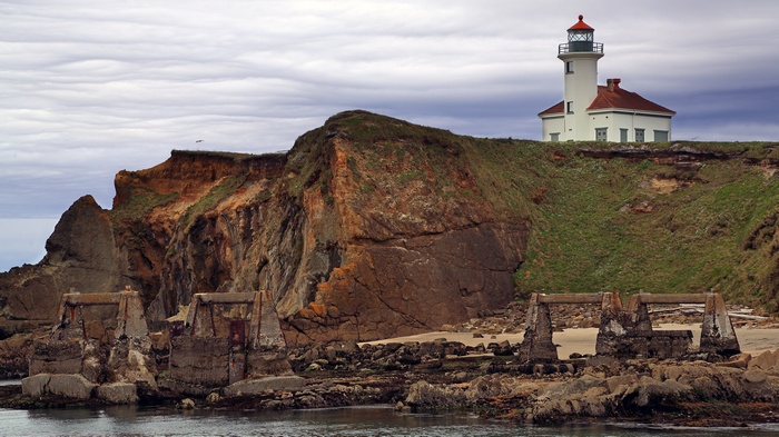 Lighthouse on a cliff overlooking the ocean with ruins
