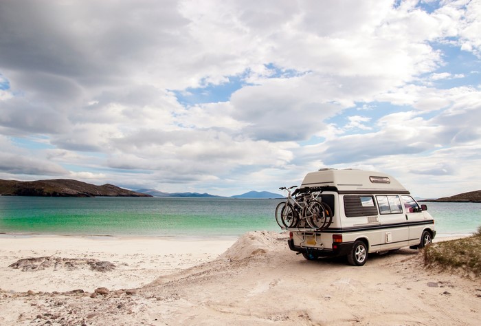 Campervan with bicycles on a beach by the sea
