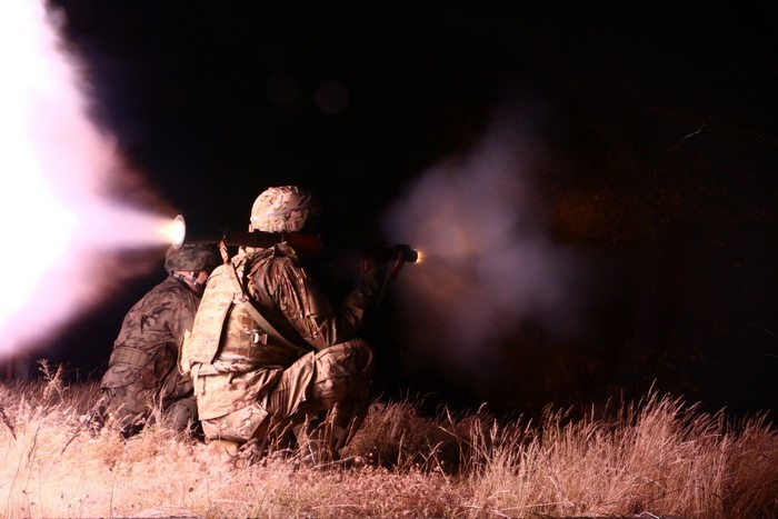 Soldiers firing a grenade launcher at night