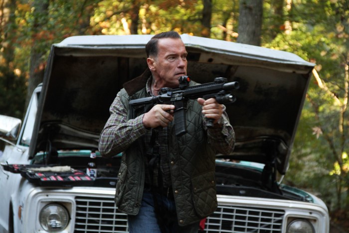 Arnold Schwarzenegger with rifle in front of truck