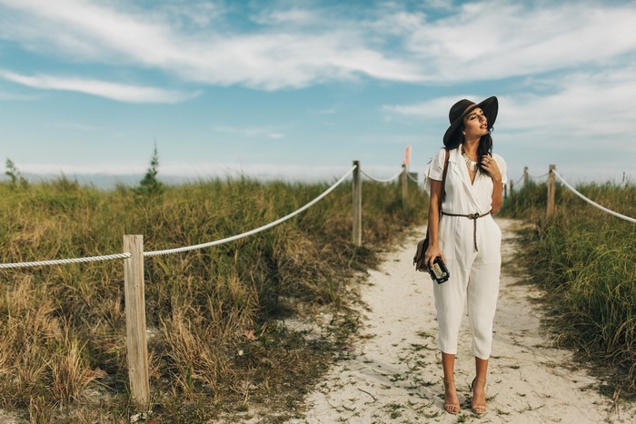 Woman in a hat and jumpsuit on a beach path