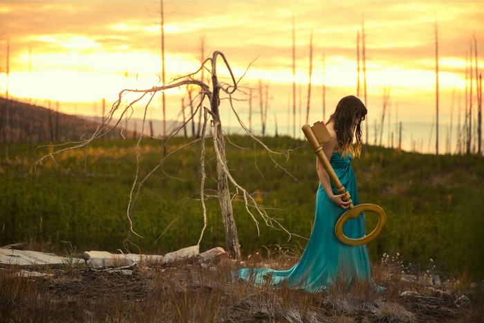 Woman in blue dress holding a large key