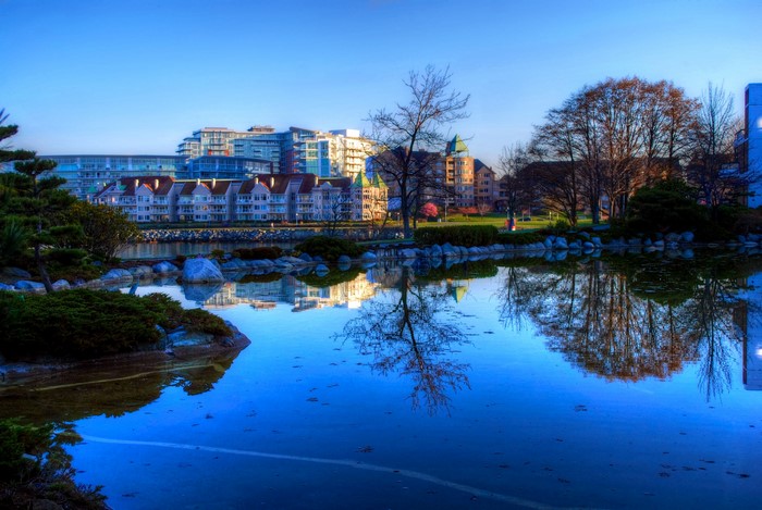 Waterfront buildings and trees reflected in a calm lake