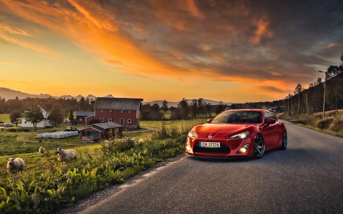 Red Toyota GT86 on a rural road at sunset