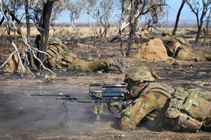 Australian soldiers firing machine guns in a dry landscape