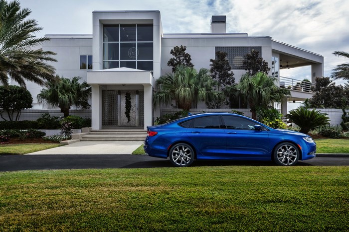 Blue 2015 Chrysler 200 S parked in front of a modern mansion