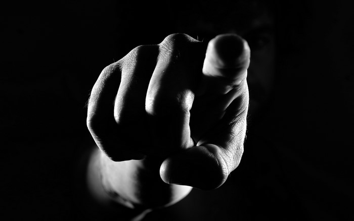 Hand pointing forward in dramatic lighting