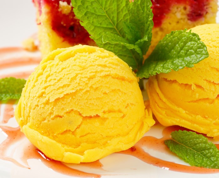 Yellow ice cream scoops with cake and mint