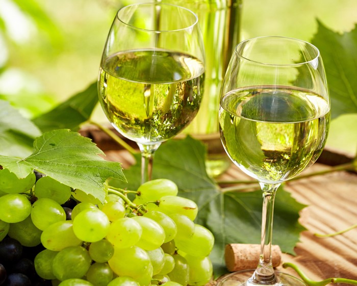 Two glasses of white wine with grapes and leaves