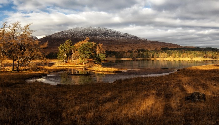 Lake Tulla, Scotland with snow-capped mountains and autumn trees