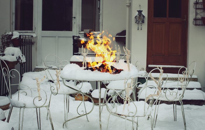 Fire on a snow-covered table with wooden dolls and chairs