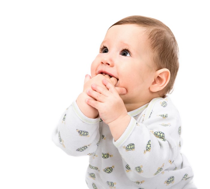Infant looking up and chewing on fingers