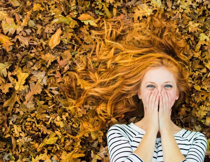 Redhead girl lying in autumn leaves