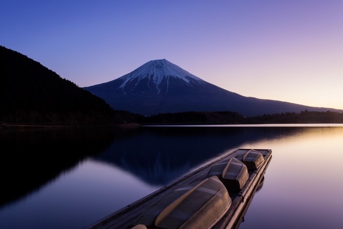 Mount Fuji and boats on a lake at dawn