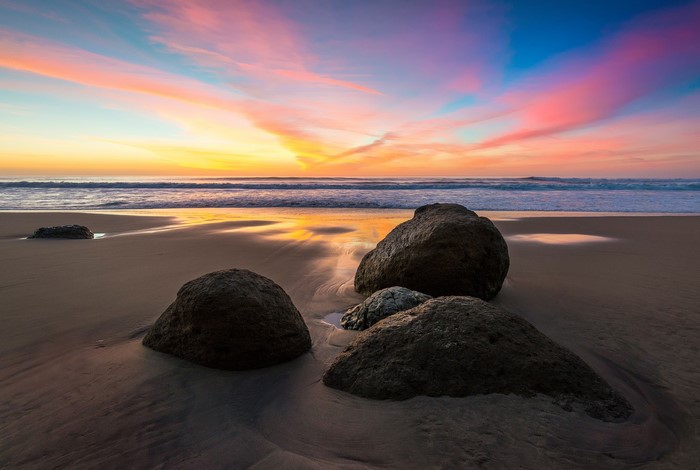 Sunset over the ocean with rocks on the beach