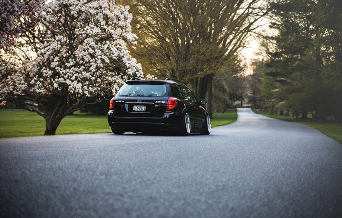Black Subaru Outback on a Tree-Lined Road