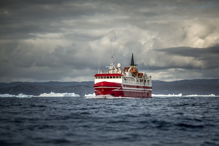Red and white ship sailing through icy waters