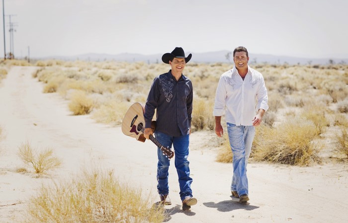 Two men with a guitar in a desert