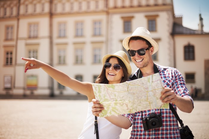 Couple with map and camera in city square