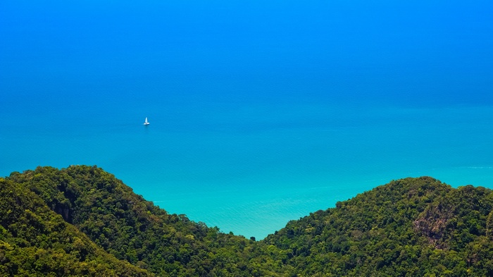 Sailboat on blue ocean with green islands